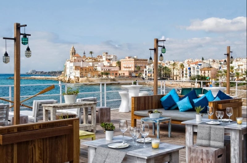 Vista de Sitges desde la hermosa terraza con diferentes muebles de madera del restaurante Viveros