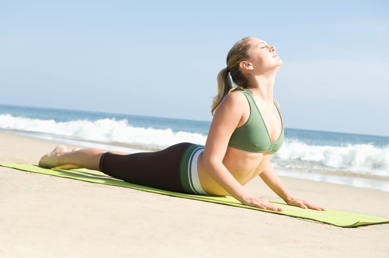 Una mujer haciendo yoga en la playa de Sitges, que es maravillosa para tomar el sol 