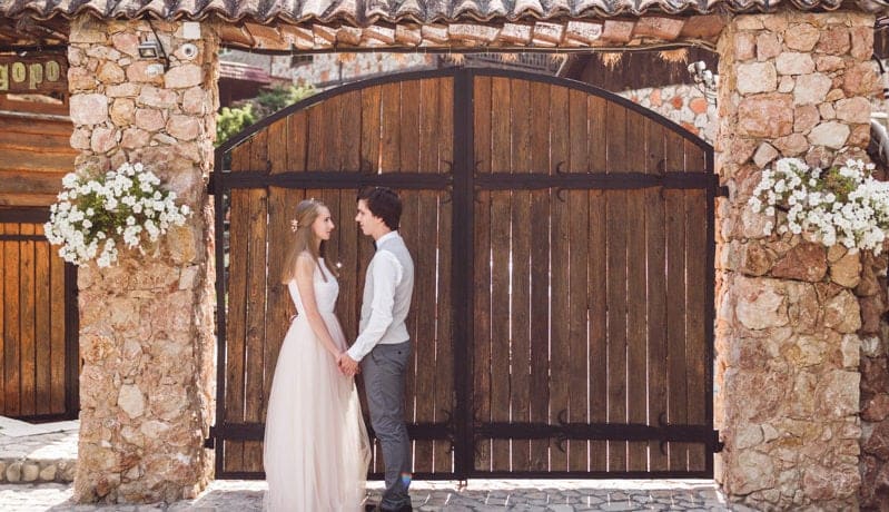Una pareja de recién casados tomados de la mano en una villa para bodas