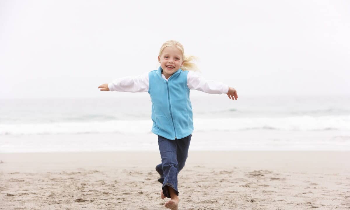 A girl running on a Sitges beach in the winter sunshine